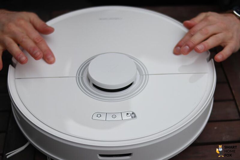 К Roborock Q7 в белом глянцевом исполнении прикасаются пальцами сверху